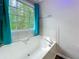 Bathtub with tile surround and a large window overlooking a green, wooded backyard at 505 Blake Dr, Douglasville, GA 30134
