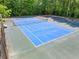 A pristine blue tennis court nestled between basketball courts and lush trees, offering residents a scenic recreational space at 1552 Brentwood Dr, Marietta, GA 30062