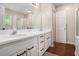 Bathroom featuring double sinks, white cabinetry, dark wood flooring, and a bright mirror at 300 Alcovy Way, Covington, GA 30014