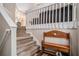 Warm entryway with carpeted stairs, wooden bench, and white railings, offering a cozy and inviting welcome at 300 Alcovy Way, Covington, GA 30014