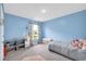 A light blue ' bedroom with gray carpet, featuring storage shelves and natural light from the window at 509 Azalea Bloom Dr, Loganville, GA 30052