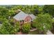 Aerial view of a stately brick home with a gray roof surrounded by mature trees and lush greenery at 6020 Ettington Dr, Suwanee, GA 30024