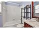 Bright bathroom featuring a white tiled shower-tub, dark metal shelving, and vanity with a marble countertop at 6020 Ettington Dr, Suwanee, GA 30024