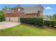 Side view of a brick home with a spacious garage, lush green lawn, and mature landscaping at 6020 Ettington Dr, Suwanee, GA 30024