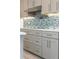 Stylish kitchen with gray cabinets and drawers, and a sleek blue tile backsplash at 911 Lenox Hill Ne Ct, Atlanta, GA 30324