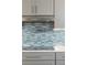 Close up of kitchen counter with blue tiled backsplash and sleek range hood at 911 Lenox Hill Ne Ct, Atlanta, GA 30324