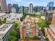 Expansive aerial view showcasing a classic brick apartment building nestled among trees in a vibrant urban landscape at 1325 Peachtree Ne St # 401, Atlanta, GA 30309