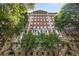 Stately brick apartment building framed by mature trees, showcasing its classic architectural details at 1325 Peachtree Ne St # 401, Atlanta, GA 30309