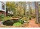 Tranquil backyard with a serene pond, mature trees, lush greenery, and a charming brick pathway at 769 Hampton Sw Pl, Marietta, GA 30064