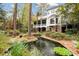Secluded backyard featuring a covered porch, lush landscaping, brick accents, and tranquil creek water feature at 769 Hampton Sw Pl, Marietta, GA 30064