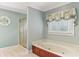 Bright bathroom featuring a soaking tub with wood trim, a window, and a separate shower with a gold frame at 769 Hampton Sw Pl, Marietta, GA 30064