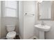 Well-lit powder room features a pedestal sink, classic toilet, and neutral decor at 2091 Landsburg Way, Lawrenceville, GA 30043