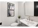 Elegant powder room featuring a pedestal sink, modern fixtures, and stylish artwork, creating a sophisticated ambiance at 522 Pearl St, Cumming, GA 30040