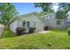 A quaint backyard shows a house with light-blue siding, a stone patio, green grass, and lush bushes at 1283 Mercer Ave, East Point, GA 30344