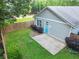 A grassy backyard with a small stone patio and a light-gray house with a blue door is fenced in at 1283 Mercer Ave, East Point, GA 30344