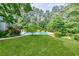 Expansive backyard features a lush green lawn, in-ground pool, and mature trees, perfect for outdoor activities at 1550 Masters Club Dr, Sandy Springs, GA 30350