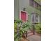 Two-story home with a bright pink door, green siding, and brick steps at 6 Holly Downs Nw Ct, Atlanta, GA 30318