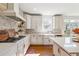 Bright kitchen featuring white cabinets, stainless steel appliances, and natural stone backsplash at 6640 Stratford Pl, Cumming, GA 30040