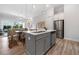 Open-concept kitchen with gray island, stainless steel appliances, and wood floors, flowing into the dining and living areas at 677 Stickley Oak Way, Woodstock, GA 30189