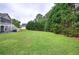 Wide shot of a beautiful backyard featuring a large grassy area, mature trees, and a home with a screened-in porch at 18 Spring Lake Ne Trl, White, GA 30184