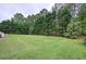 Picturesque backyard with lush green lawn, bordered by mature trees, offering a serene outdoor space at 18 Spring Lake Ne Trl, White, GA 30184
