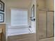 Bright bathroom features a soaking tub, shower, and large window with blinds at 18 Spring Lake Ne Trl, White, GA 30184