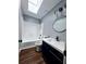 Modern bathroom with a white tub, black hardware, stylish blue vanity and round mirror at 3647 Diamond Cir, Decatur, GA 30034