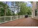 This large deck features wood floors and white railings overlooking mature trees in the backyard at 5293 Aldeburgh Dr, Suwanee, GA 30024