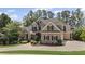 Lovely brick home with a manicured lawn, mature trees, dark shutters and a wide driveway at 5293 Aldeburgh Dr, Suwanee, GA 30024