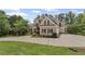 Brick home with professional landscaping, a spacious driveway, and mature trees at 5293 Aldeburgh Dr, Suwanee, GA 30024
