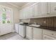 Bright laundry room with white cabinets, granite counters, stainless sink, and front load washer and dryer at 5293 Aldeburgh Dr, Suwanee, GA 30024