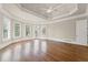 Large main bedroom with hardwood floors, ceiling fan, tray ceiling, and access to balcony at 5293 Aldeburgh Dr, Suwanee, GA 30024
