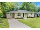 Well-maintained ranch-style home with a concrete driveway and a green lawn, nestled among mature trees at 2308 Scotty Cir, Decatur, GA 30032