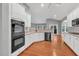 Charming kitchen features white cabinets, hardwood flooring, black appliances and plenty of natural light at 2825 Harbor Cove Ct, Cumming, GA 30041
