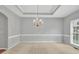 Sunlit living room featuring elegant chandelier, neutral walls, and plush carpeting at 2825 Harbor Cove Ct, Cumming, GA 30041