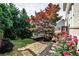 Landscaped backyard featuring vibrant pink flowers, lush trees, and a charming wooden deck at 11760 Stratham Dr, Alpharetta, GA 30009