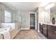 Modern bathroom features a glass-enclosed shower, soaking tub, double vanity and tile flooring at 11760 Stratham Dr, Alpharetta, GA 30009