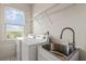 Bright laundry room with modern washer, dryer, sink, storage rack, and a large window at 629 Boulevard Ne, Atlanta, GA 30308