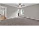 A large bedroom with neutral paint and plush carpet. It also features a window offering natural light at 1774 Northwick Pl, Lithonia, GA 30058