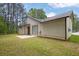 Backyard view of tan home with patio, green grass, and plenty of trees at 1774 Northwick Pl, Lithonia, GA 30058