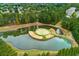 Aerial view showcases a golf course with pond and central island green, complemented by mature trees and local roadways at 301 Downing Creek Trl, Canton, GA 30114
