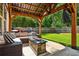 Covered patio with stone fire pit, plush seating, and view of the expansive, well-manicured yard at 301 Downing Creek Trl, Canton, GA 30114