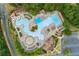 Aerial view of a resort style pool with waterslides, a splash pad, lap pool, and lounge areas surrounded by trees at 301 Downing Creek Trl, Canton, GA 30114
