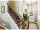 Elegant staircase with wooden handrail, iron balusters, and carpeted steps leading to the upper level with a front door view at 301 Downing Creek Trl, Canton, GA 30114