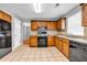 Spacious kitchen featuring wood cabinetry, granite countertops, tile floors, and black appliances at 4000 Crossings Way, Stone Mountain, GA 30083