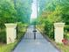 View of the black metal entrance gate leading to the tree-lined driveway of the property at 3340 Zingara Rd, Conyers, GA 30012