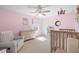 Pink Bedroom with two cribs, comfortable armchair, changing table, and window at 496 Spring View Dr, Woodstock, GA 30188