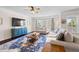 Bright living room with large windows, plush sofas, decorative rug, and a ceiling fan at 496 Spring View Dr, Woodstock, GA 30188
