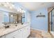 Bright bathroom with double granite vanity, tile floors, framed mirrors, and a glass-enclosed shower at 496 Spring View Dr, Woodstock, GA 30188