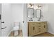 Well-lit bathroom with a toilet and double vanity featuring wooden cabinets and contemporary fixtures at 6895 Smoke Ridge Dr, Atlanta, GA 30349